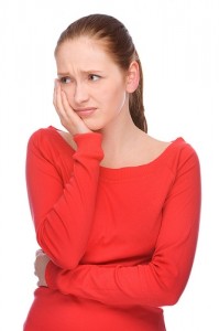 A woman with a tooth ache holds the side of her face.